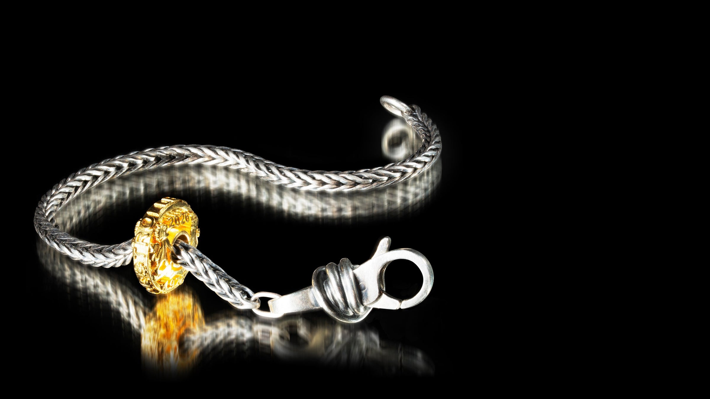 Silver bracelet with a gold clasp on a black background